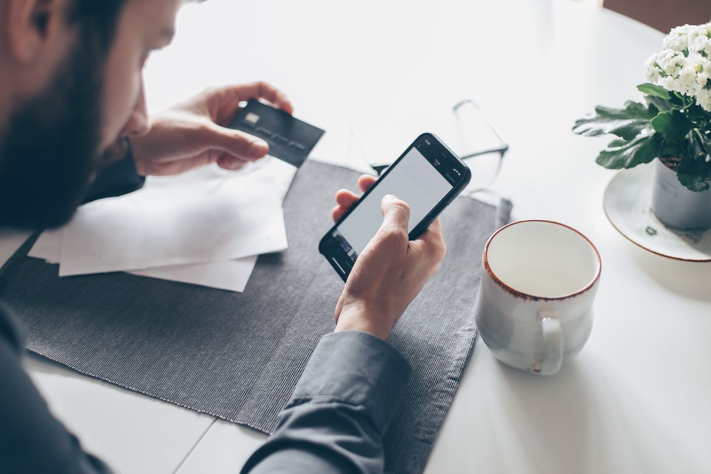 A customer at a table with a card and a phone, paying an invoice