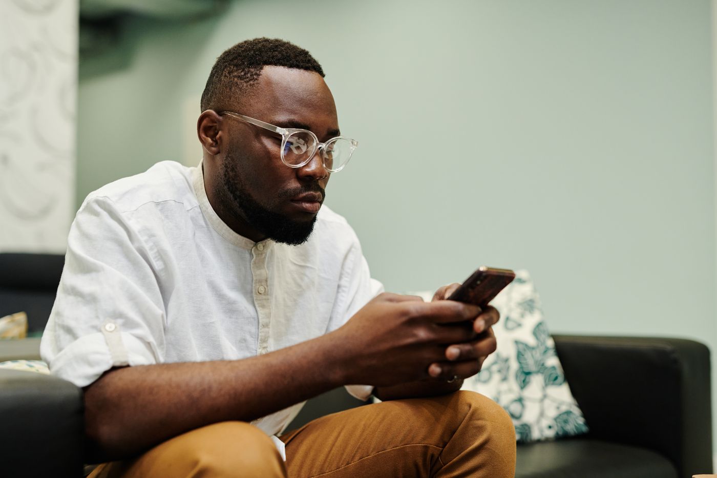 A customer sitting on a sofa, typing a message on his phone